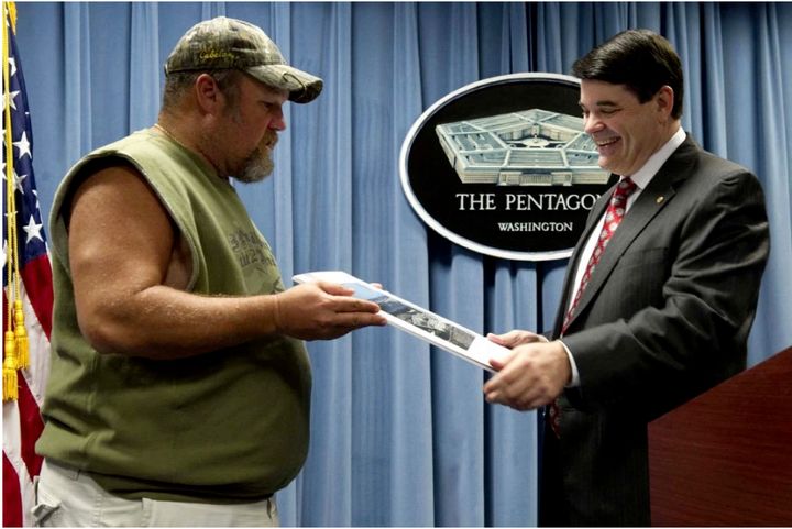 The picture in question from the Washington Post, Principal Deputy Assistant Secretary of Defense Bryan Whitman, presenting a challenge coin to comedian Larry the Cable Guy.