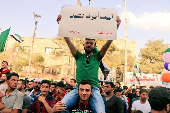 A young man holds a placard during one of the peaceful protests organized in Maarat al-Numan that says, 'The people are the strongest faction'. June 20, 2016.