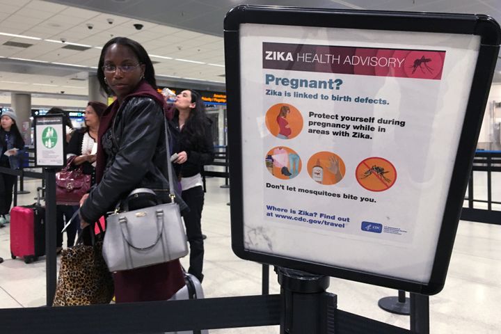 A woman looks at a Center for Disease Control health advisory sign about the dangers of the Zika virus as she lines up for a security screening at Miami International Airport in May 2016.