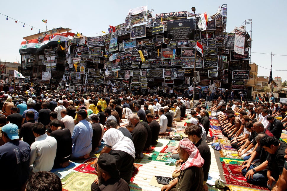Iraqis attend Friday prayers during Eid al-Fitr at the site of last weekend's car bomb attack in Baghdad.