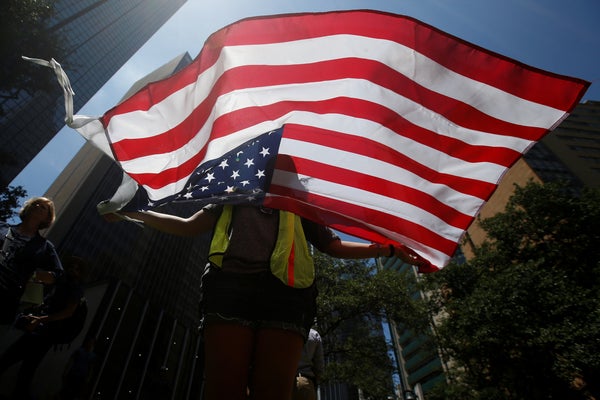 A woman holds a U.S. flag during a prayer vigil in a park following the multiple police shooting in Dallas, Texas, U.S., July