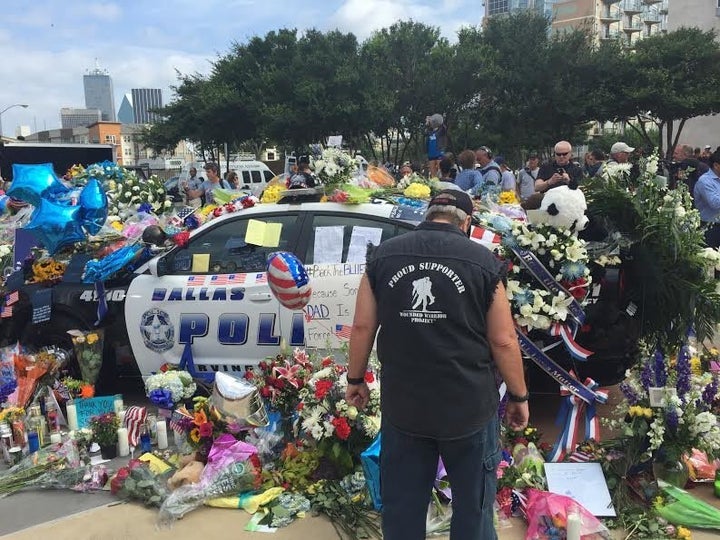 A man stands at an impromptu memorial set up outside the Dallas Police Department on Saturday.