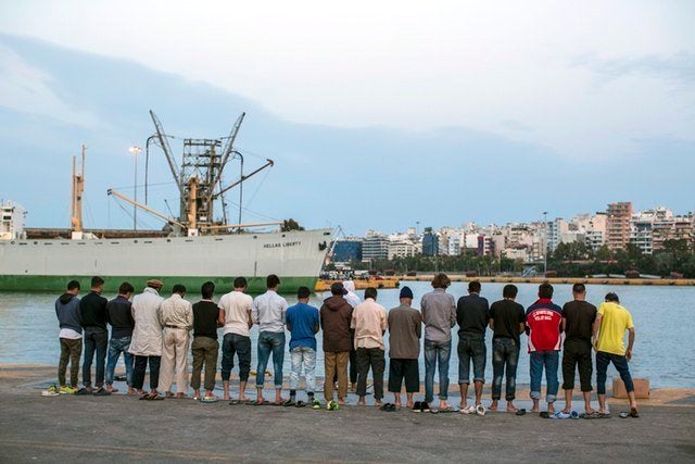 A group of Muslim men line up by the docks of the Athenian port of Piraeus to perform evening prayer.