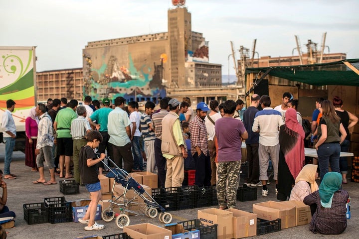 Refugees queue up at sunset in the port of Piraeus for the thrice-daily food handouts coordinated by the Greek army through a