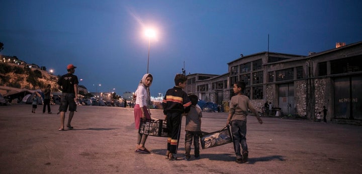 Members of a family walk back from communal taps to their tent in the temporary campsite at the port of Piraeus, close to whe