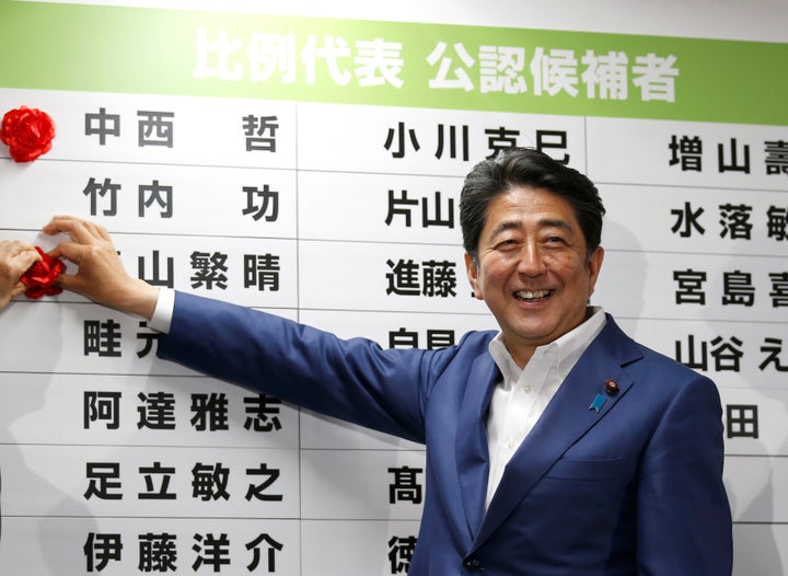 Japan's Prime Minister Shinzo Abe, leader of the ruling Liberal Democratic Party (LDP), puts a rosette on the name of a candidate who is expected to win the upper house election.