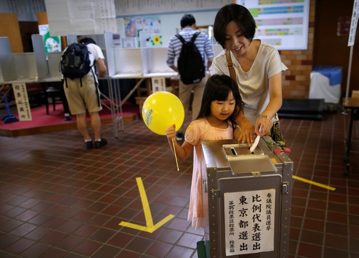 A girl looks on as her mother casts her ballot for Japan's upper house election at a polling station in Tokyo, Japan July 10,
