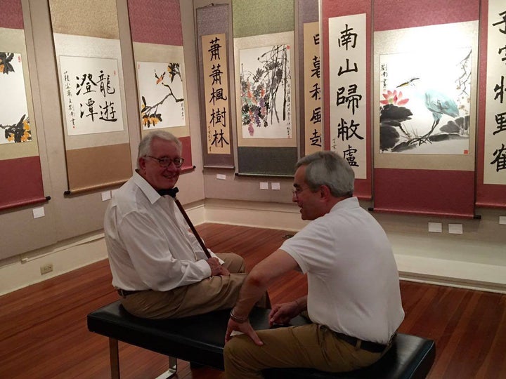 Visitors to Nan Liu's exhibition with examples of his brush paintings. 