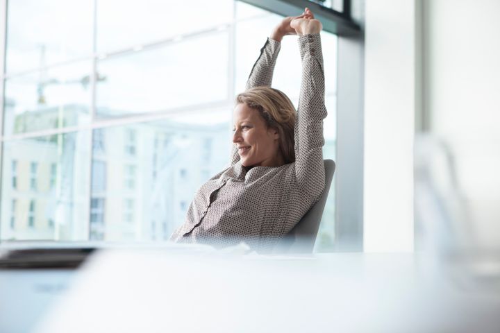 Businesswoman in office stretching Westend61 via Getty Images