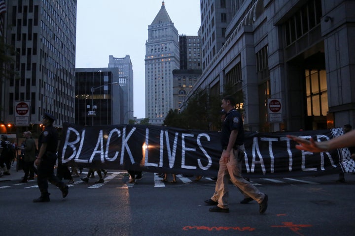 Policemen walk on the sidelines as protesters hold a sign which states "Black Lives Matter," during a march against police brutality in Manhattan, New York, U.S., July 9, 2016.