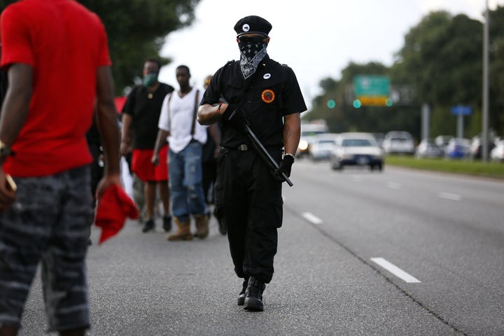 A demonstrator wearing the insignia of the New Black Panthers Party carries a shotgun during a protest over the shooting deat
