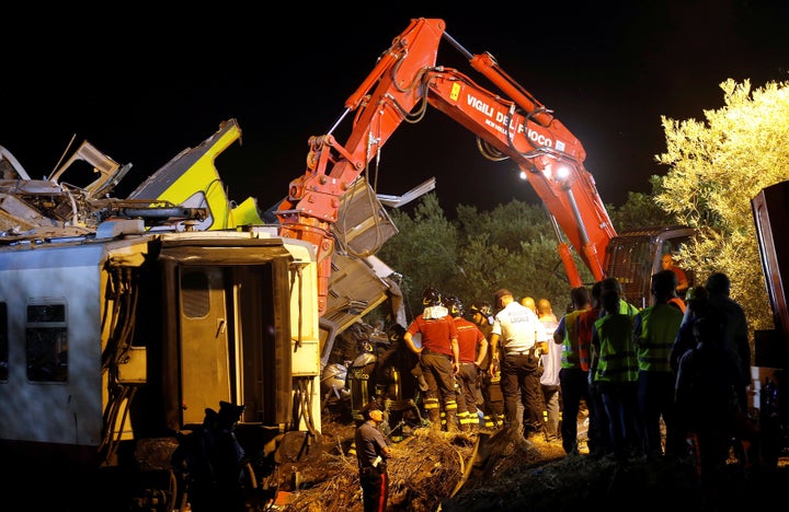 Rescuers work at the site where two passenger trains collided in the middle of an olive grove in the southern village of Cora