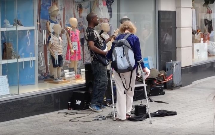 The woman is seen standing in front of the busker