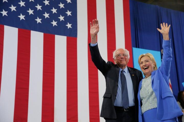Democratic U.S. presidential candidates Hillary Clinton and Sen. Bernie Sanders stand together during a campaign rally where