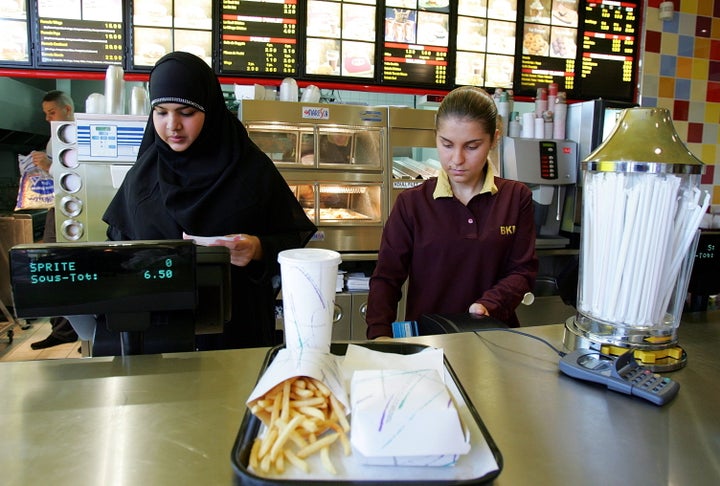 An employee (left), who gave her first name as Nora, prepares a food order at the counter of Beurger King Muslim, or BKM, in