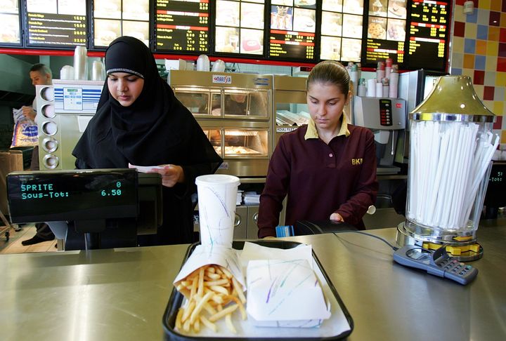 An employee (left), who gave her first name as Nora, prepares a food order at the counter of Beurger King Muslim, or BKM, in Clichy-sous-Bois, a suburb east of Paris, August 8, 2005.