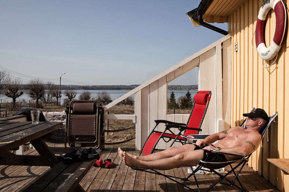 An inmate, who was sentenced to 16.5 years for murder and narcotics crimes, sunbathes in front of the wooden cottag