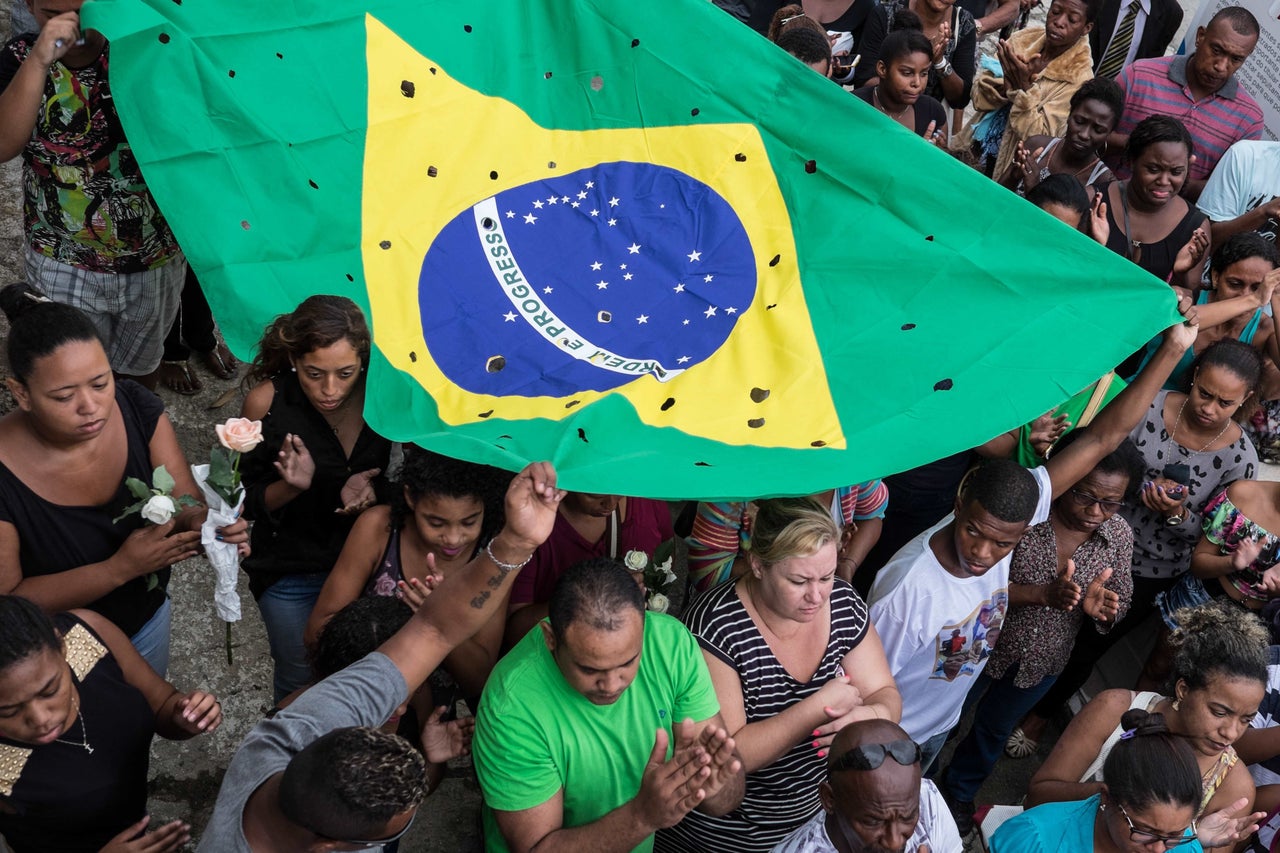 Protesters in Rio de Janeiro hold a Brazilian flag littered with holes to mark the number of shots fired at a group of young men killed by police in 2015. Police killed 645 people in Rio de Janeiro state last year, according to human rights groups.