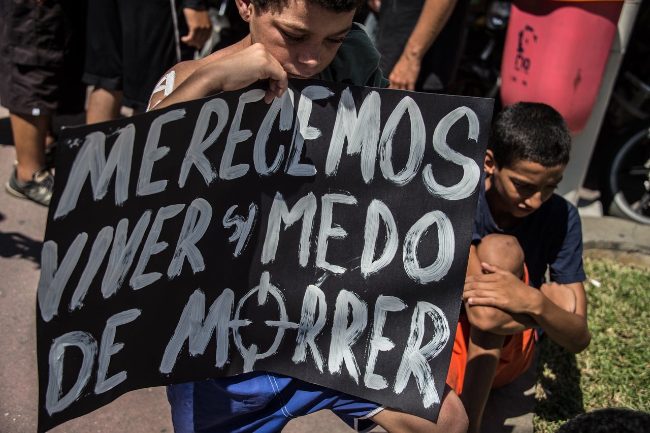 A boy holds a sign that says "We deserve to live without fear of dying," during a 2015 protest against police violence in Rio. Activists fear that new laws passed to help secure the Olympics could limit public assembly and expression rights in Brazil.