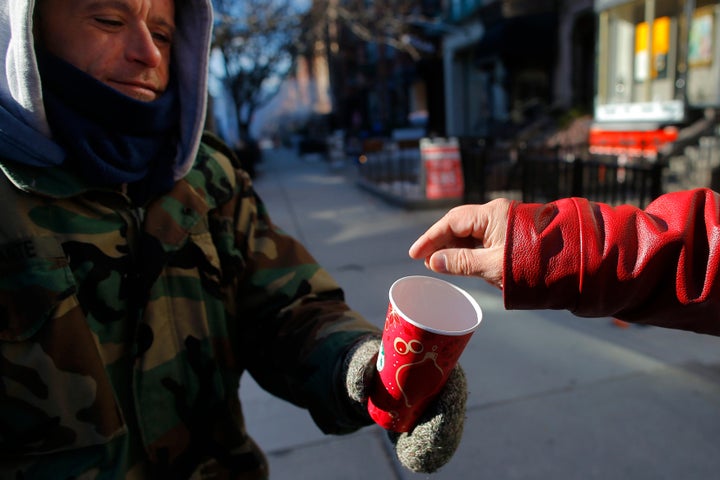 A passerby gives some money to a homeless veteran of the United States' wars in Iraq and Afghanistan, in Boston, Massachusetts.