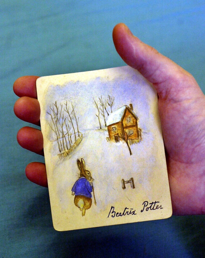 A rabbit in a blue jacket walking in snow toward a cottage at Dominic Winter Book Auctions in Swindon, England. The picture is part of a series, which are believed to be original drawings by Beatrix Potter.