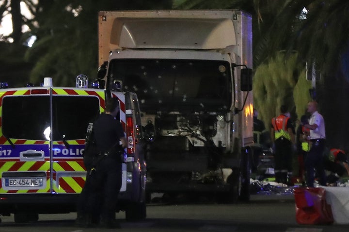 Police officers stand near a van, with its windscreen riddled with bullets, that ploughed into a crowd in Nice.