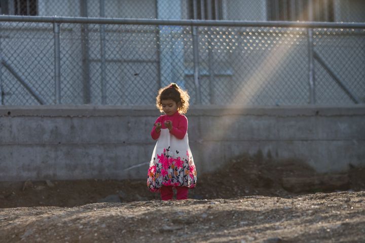 MYTILENE, GREECE - MARCH 26: A young girl stands under a shaft of sunlight at the Moria Refugee Camp on March 26, 2016 in Mytilene, Greece. New boat arrivals on the island have reduced to almost zero over the last few days, but it remains unclear whether that is due to the windy weather or the deal between the EU and Turkey. The aid agency Doctors Without Borders, or MSF (Medecines Sans Frontieres), has recently announced that it was to cease operations in the Greek refugee camp at Moira. MSF spoke out after a deal struck last week between EU states and Turkey to force migrants and asylum seekers to return from Greek islands to Turkey came into place. (Photo by Dan Kitwood/Getty Images)