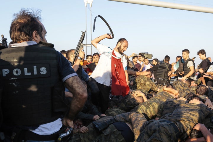 An unidentified man uses his belt to hit Turkish soldiers on Istanbul's Bosphorus bridge who were allegedly involved in