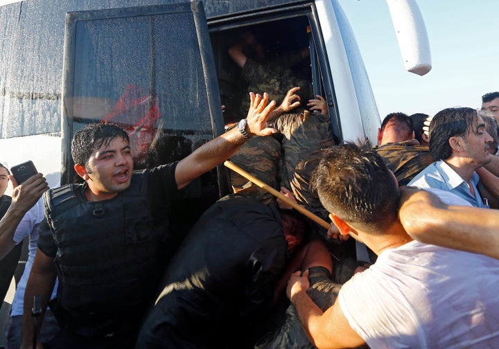 A policeman protects soldiers from the mob after troops involved in the coup surrendered on the Bosphorus Bridge.