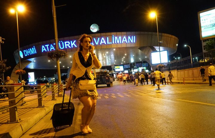 A passenger walks as army tanks enter the Ataturk Airport on July 16, 2016, in Istanbul, Turkey. Istanbul's bridges across the Bosphorus, the strait separating the European and Asian sides of the city, were closed to traffic.