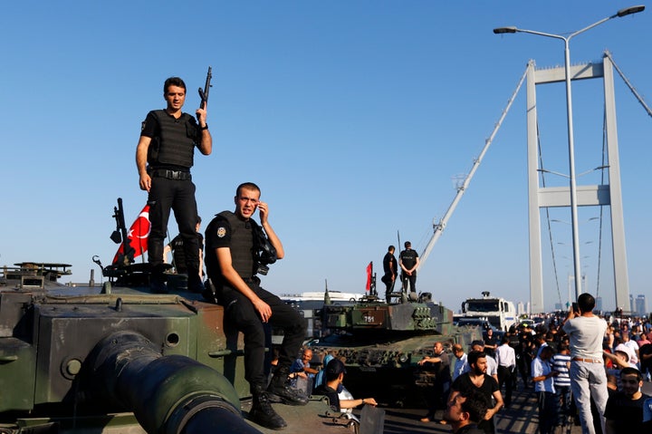 Policemen stand atop military armored vehicles after troops involved in the coup surrendered on the Bosphorus Bridge in Istan