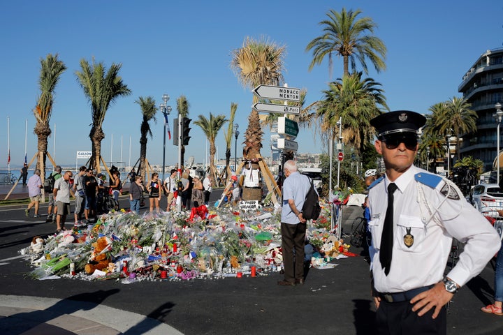 A police officer surveys people gathering around a floral tribute for the victims killed during the deadly attack on Thursday