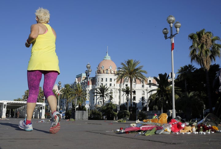 A jogger runs past flowers and candles placed in tribute to a victim of the attack