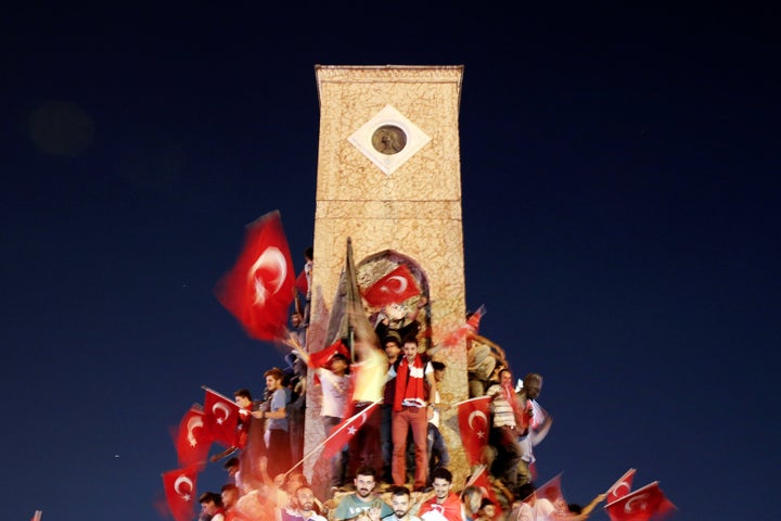 Supporters of Turkish President Tayyip Erdogan wave Turkish national flags and shout slogans as they stand around the Republi