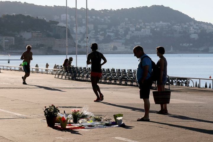 <strong>A couple watch flowers placed in tribute to one of the victims at the scene of a deadly attack while joggers pass by.</strong>