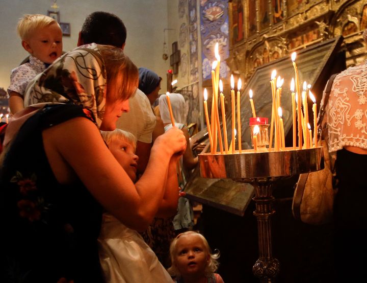 <strong>An unidentified woman and her children light candles during a mass at the Saint Nicolas Orthodox church in Nice.</strong>