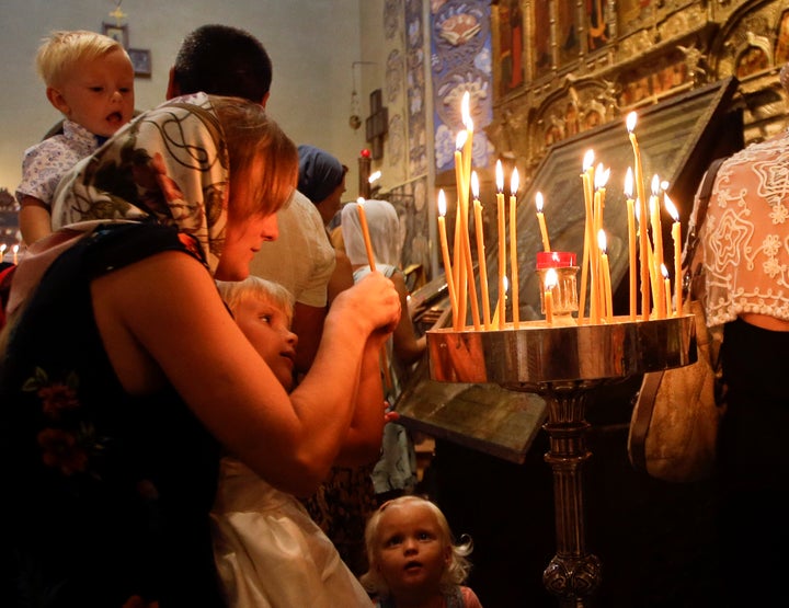 An unidentified woman and her children light candles during a mass at the Saint Nicolas Orthodox church in Nice.