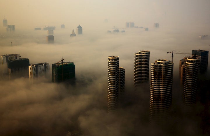 Buildings in construction are seen among mist during a hazy day in Rizhao, Shandong province, China, October 18, 2015.