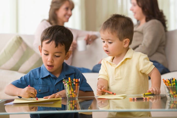 Brothers drawing together in living room KidStock via Getty Images