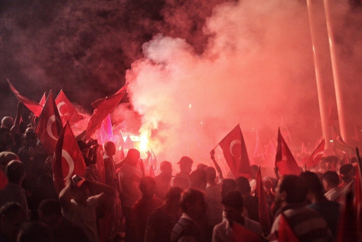 Supporters of Turkish President Tayyip Erdoğan light flares as they gather in Istanbul's central Taksim Square on July 18, 20