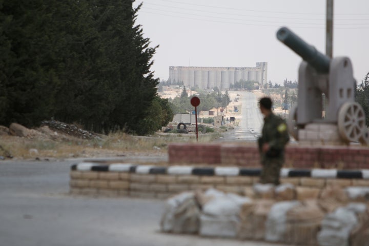 A fighter from the Syria Democratic Forces (SDF) stands with his weapon at the western entrance to Manbij city, in Aleppo Gov