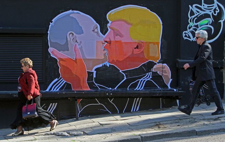 People walk past a mural on a restaurant wall depicting presidential hopeful Donald Trump and Russian President Vladimir Putin greeting each other with a kiss in the Lithuanian capital Vilnius on May 13, 2016.