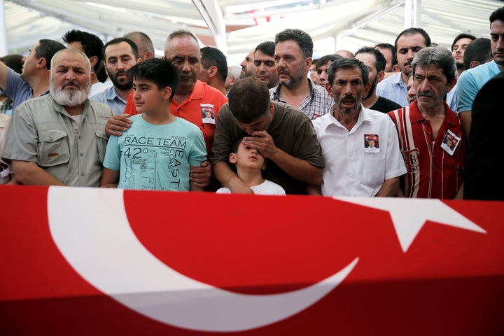 A man comforts the son of Erol Ince, a police officer who was killed during a thwarted coup, during a funeral ceremony at Ist