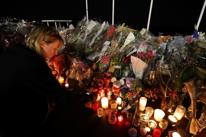 A woman lights a candle on July 18, 2016 in Nice, by the new makeshift memorial in tribute to the victims of the deadly Bastille Day attack.