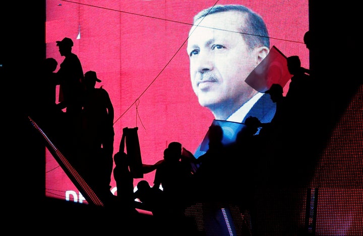Turkish supporters are silhouetted against a screen showing President Recep Tayyip Erdogan during a pro-government