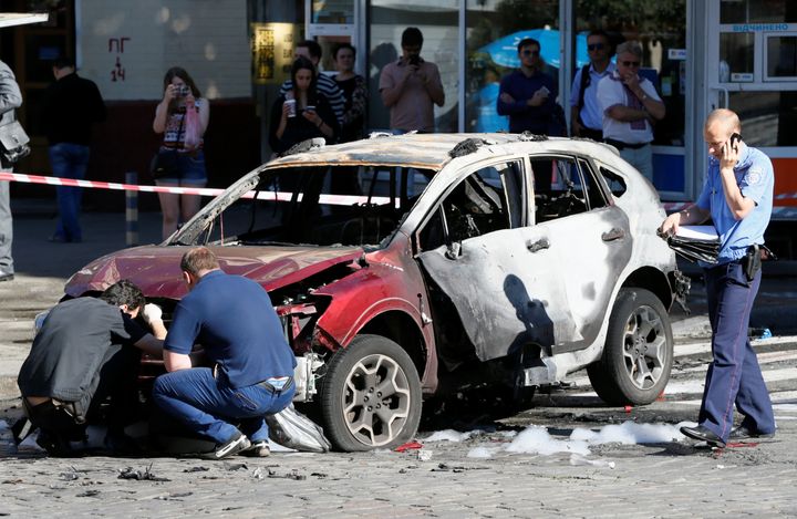 Investigators inspect a damaged car at the site where journalist Pavel Sheremet was killed by a car bomb in central Kiev, Ukraine on Wednesday.