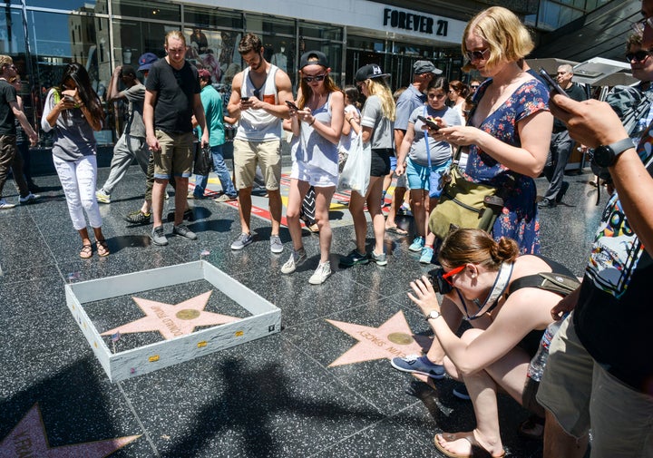 Onlookers take photos of the Plastic Jesus installation -- a miniature wall -- built around Donald Trump's Hollywood Walk of