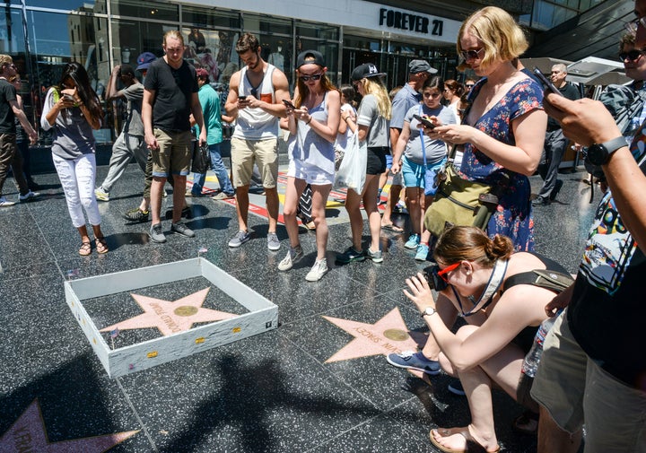 Onlookers take photos of the Plastic Jesus installation -- a miniature wall -- built around Donald Trump's Hollywood Walk of Fame star.