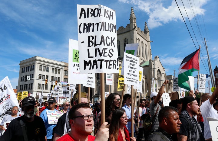 Demonstrators hold placards during a march by various groups, including "Black Lives Matter" and "Shut Down Trump and the RNC