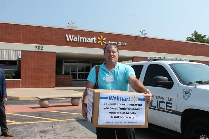 Food activist Jordan Figueiredo holds a box full of petition signatures of outside Walmart headquarters in Bentonville, Arkansas.